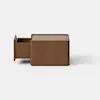 A small, square wooden box sits on a white surface with a plain light gray background.