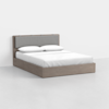 A modern queen-sized bed with a light wood frame and a gray upholstered headboard, dressed in white bedding and pillows, placed in a minimal, bright room with a plain white background.