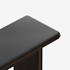 A close-up view of a dark gray upholstered bench seat with a smooth wooden frame, shown against a plain white background.