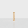 A minimalist wooden shelving unit with three shelves, standing alone on a light grey floor against a plain white background.