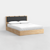 A modern wooden bed with a light wood frame, white bedding, two pillows, and a padded dark gray headboard against a plain white background.