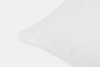 Close-up of the corner of a white textured pillow against a plain light background, showing a soft quilted fabric with a subtle grid pattern.