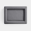 A rectangular, gray, upholstered cushion or ottoman viewed from above against a plain white background. The fabric appears textured and the edges are rounded and padded.