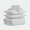Neatly folded light gray bedding set including two pillowcases, a duvet cover, and sheets, stacked on a plain white background.