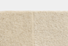 Close-up of two beige carpet textures side by side; the left side is plush and soft while the right side has a looped, woven pattern. Both are similar in color, but differ in texture and weave style.