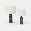 Two modern table lamps with cylindrical white fabric shades and dark marbled bases, one larger and one smaller, displayed against a plain white background.