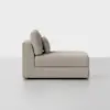 A modern beige chaise lounge with two large back cushions and one smaller pillow sits against a plain light gray background.