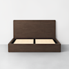 A minimalist wooden bed frame with a tall, solid headboard and visible slatted base, finished in a dark brown color, placed in an empty room with light gray flooring and white walls.