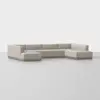A modern, light beige sectional sofa with clean lines and a low-profile design, arranged in an L-shape on a smooth, light gray floor against a plain white background.