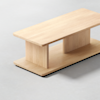 A minimalist wooden coffee table with a rectangular top, two rectangular vertical supports, and a matching rectangular base, all made from light-colored wood, on a light surface.