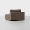 A modern, armless brown fabric chair with a low backrest, clean lines, and a boxy silhouette is shown on a light gray floor against a plain white background.
