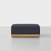 A modern, rectangular ottoman with a textured dark blue cushion and a light wooden base, set against a plain white background.