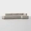 A modern, light beige sectional sofa with a low backrest and minimalist design, arranged in an L-shape on a smooth, light-colored floor against a plain white background.