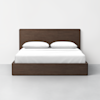 A modern wooden bed frame with a headboard, white sheets, and two white pillows, positioned against a plain white wall on a light gray floor.