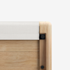 Close-up of the corner of a wooden frame with a rounded edge, showing a white fabric panel attached at the top and black hardware securing the structure. The background is plain white.