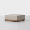 A white square ottoman with wooden legs.