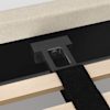 Close-up of a bed frame showing a black metal support bracket attached to the headboard, with wooden slats and a black fabric strap visible in the foreground.