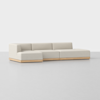 A modern, minimalist sectional sofa with light beige upholstery and a low wooden base, set against a plain white background.