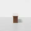 A minimalist rectangular table with a light-colored top and a solid wooden base, photographed against a plain white background.