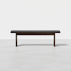 A modern, dark wooden bench with a simple rectangular seat and straight legs, set against a plain white background.