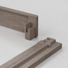 Two pieces of light brown wood with interlocking joinery, designed to fit together at a right angle, are placed on a smooth, light gray surface.