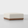 A white square ottoman on a white surface.