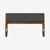 A modern wooden bench with angled legs and a cushioned, dark gray upholstered seat back, photographed against a plain white background.