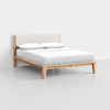 A minimalist wooden bed frame with a light upholstered headboard, neatly made with white bedding and two white pillows, set against a plain white background.
