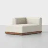 A modern, minimalist cream-colored corner sofa with a low wooden base, set against a plain light gray background. The sofa has clean lines and a boxy design.