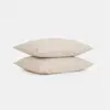 Two beige rectangular pillows stacked neatly on top of each other against a plain white background.