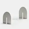 Two metal bookends with a minimalist design, each featuring a rounded arch shape and a vertical rectangular cutout in the center, placed on a plain white background.