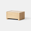 A minimalist wooden storage box with smooth edges and a light natural finish, placed on a light gray surface against a plain white background.