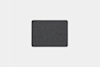 A rectangular, dark gray felt mat with rounded corners is centered on a plain light gray background.