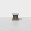 A modern, square wooden coffee table with a solid base and minimalist design, placed on a light, smooth floor against a plain white background.
