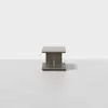 A modern, square wooden coffee table with a solid base and minimalist design, placed on a light, smooth floor against a plain white background.