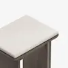 A close-up view of a modern wooden stool with a light-colored, cushioned seat against a plain white background.