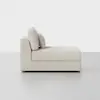 A modern, light beige chaise lounge with clean lines and two back cushions, positioned against a plain white background.