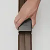 A hand slides a black connector labeled THUMA onto two dark wooden slats against a white background.