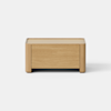 A rectangular wooden box with simple, clean lines sits on a light, smooth surface against a plain white background.
