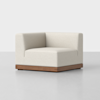 A modern corner chair with light beige upholstery and a wooden base, set against a plain, light gray background.