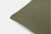 A close-up of a green textured pillow with a grid pattern, shown on a white background.