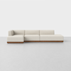 A modern, minimalist sectional sofa with cream-colored cushions and a low wooden base, placed on a light gray floor against a plain white background.