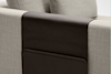 A close-up of a light beige fabric sofa arm with a dark brown leather armrest cover, which includes a built-in pocket for storage.