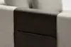 A close-up of a light beige fabric sofa arm with a dark brown leather armrest cover, which includes a built-in pocket for storage.