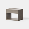 A modern wooden nightstand with a single drawer and an open lower shelf, featuring clean lines and a light grayish-brown finish, set against a plain white background.