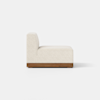A modern armless sofa chair with light beige upholstery and a wooden base, shown from the back and side, on a plain light background.