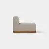 A modern armless beige sofa section with a thick cushioned seat and backrest, supported by a wooden base, shown from the side against a plain light background.