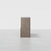A wooden cabinet with a minimalist design, shown from the side against a plain white background. The cabinet has a smooth, flat surface and subtle handles.