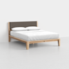 A modern wooden bed frame with a fabric-upholstered headboard, neatly made with white bedding and two white pillows, set against a plain white background.