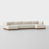 A modern, L-shaped sectional sofa with cream-colored cushions and a wooden base, set against a plain, light gray background.